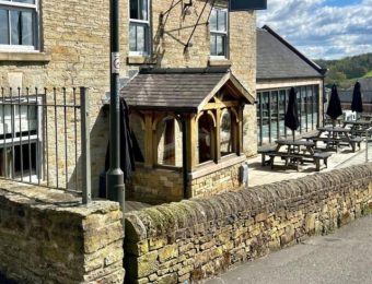 Stone-clad country pub with outdoor seating and sign reading Bluebell under a partly cloudy sky