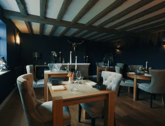 Cosy restaurant interior with wooden beams, elegant chairs, and candlelit tables in a stylish and intimate setting