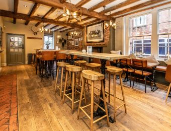 Rustic pub interior with wooden stools, beams and cosy seating, ambient lighting creating a warm, inviting atmosphere