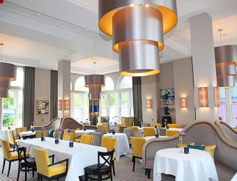 Elegant restaurant interior with yellow chairs, white tablecloths, and modern lighting fixtures