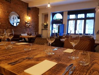Cosy restaurant interior with rustic wooden tables set with glasses and cutlery, brick walls and ambient lighting