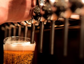 Hand pouring fresh beer from tap into a glass in a pub setting