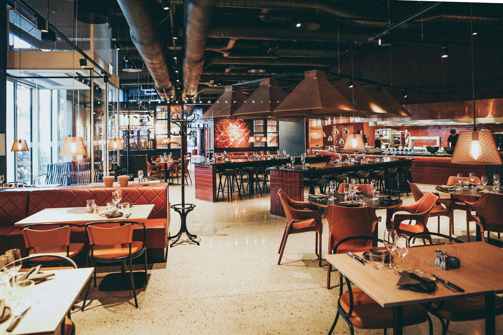 Modern restaurant interior with stylish decor, wooden tables, red booths, and ambient lighting for a cosy dining experience