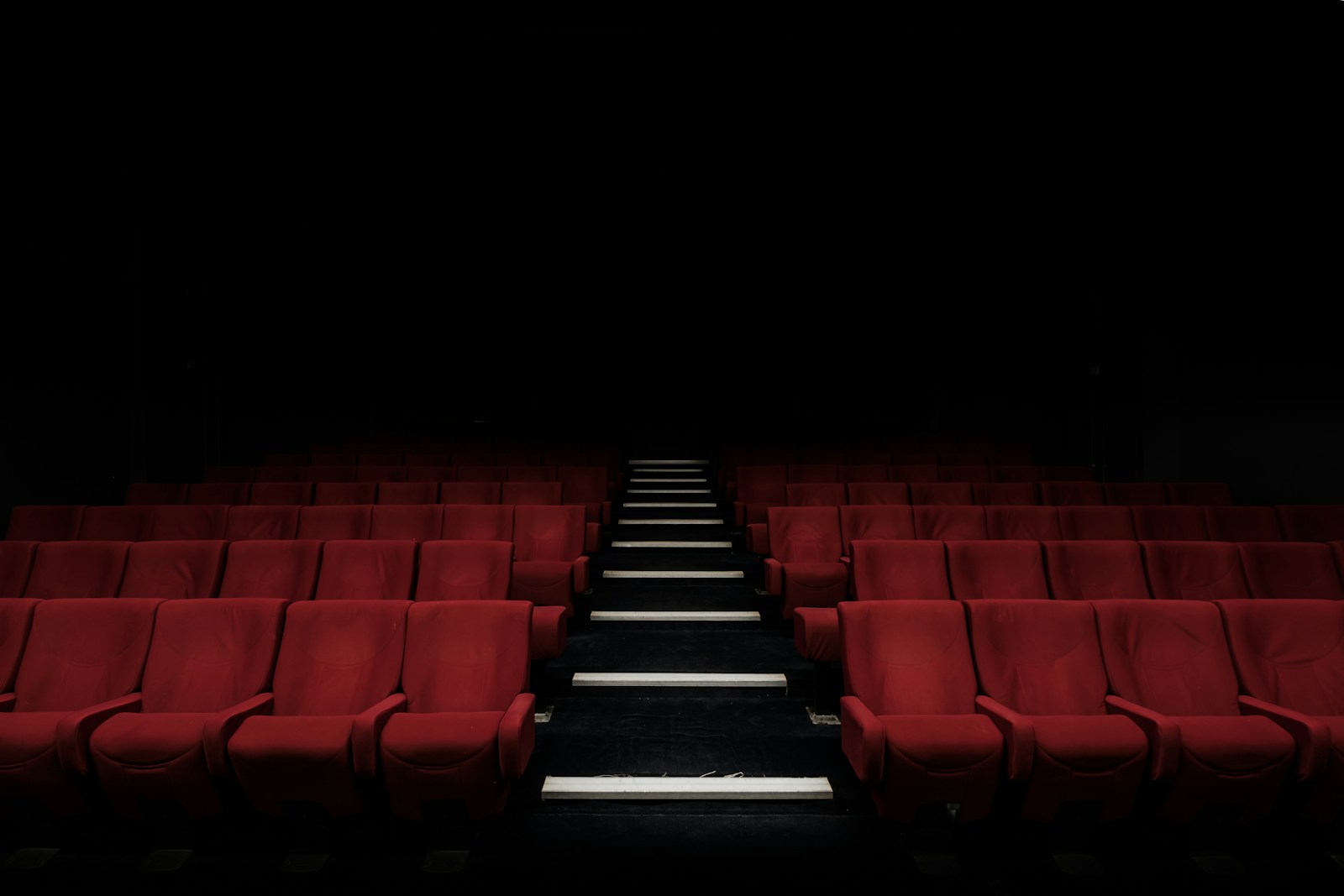 Empty cinema with red seats and dark ambiance, highlighting theatre seating arrangement and atmosphere