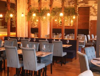 Elegant restaurant interior with modern decor, blue chairs, wooden accents, and ambient lighting for a cosy dining experience