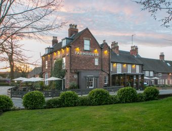 Charming countryside pub with outdoor seating and lush garden at sunset in front of a traditional brick building
