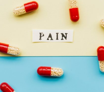 Pain pills scattered on a vibrant blue and yellow background, highlighting their colors and shapes